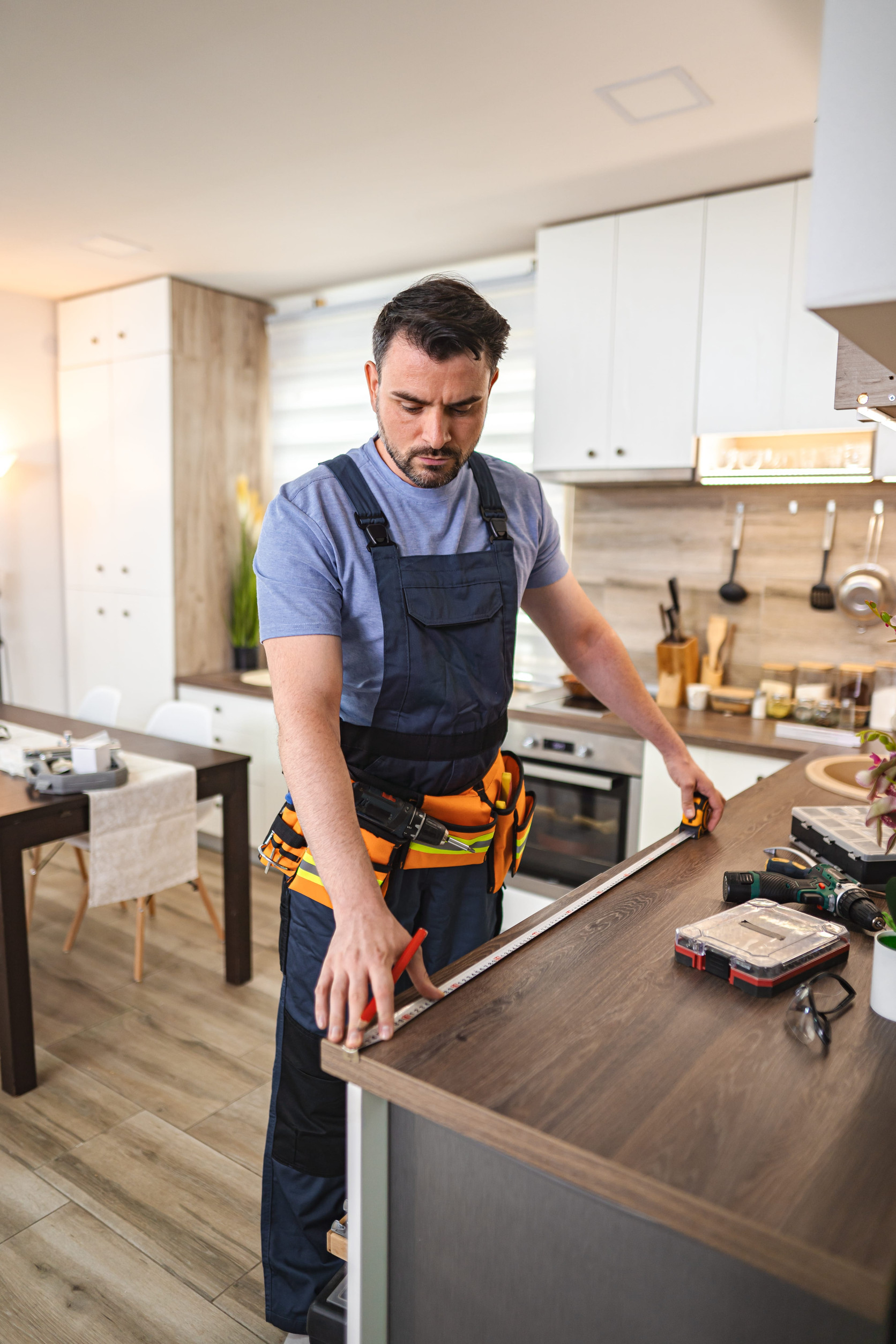 Carpenter measuring wooden kitchen countertop using tape measur